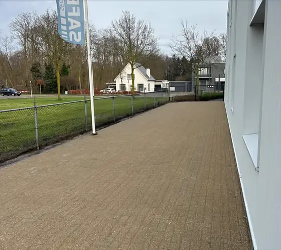 Gereinigd klinkerpad langs een bedrijfspand met vlaggenmasten